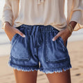 Lightweight and loose-fitting denim shorts with large pockets and fringed details.